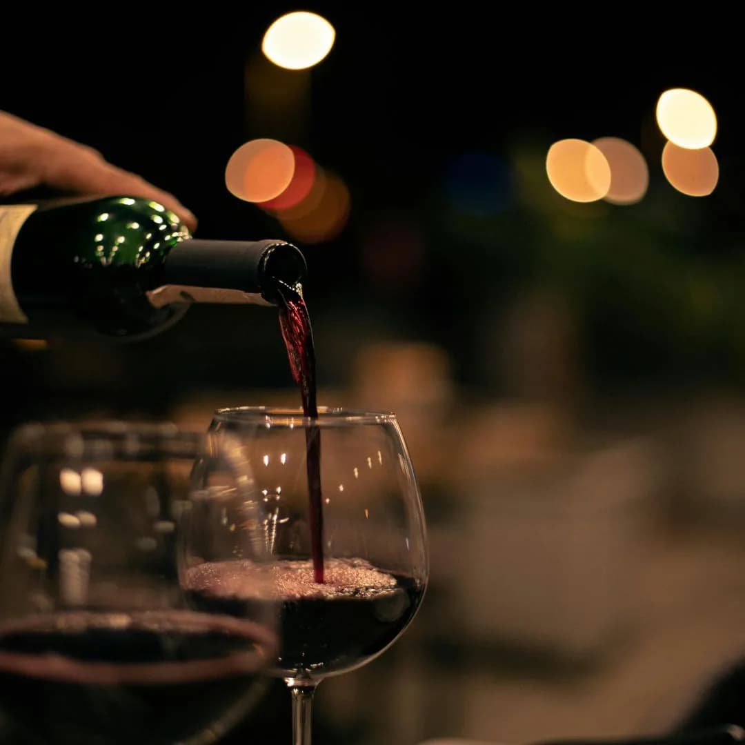 Vino rosso versato nel calice, di sera.
