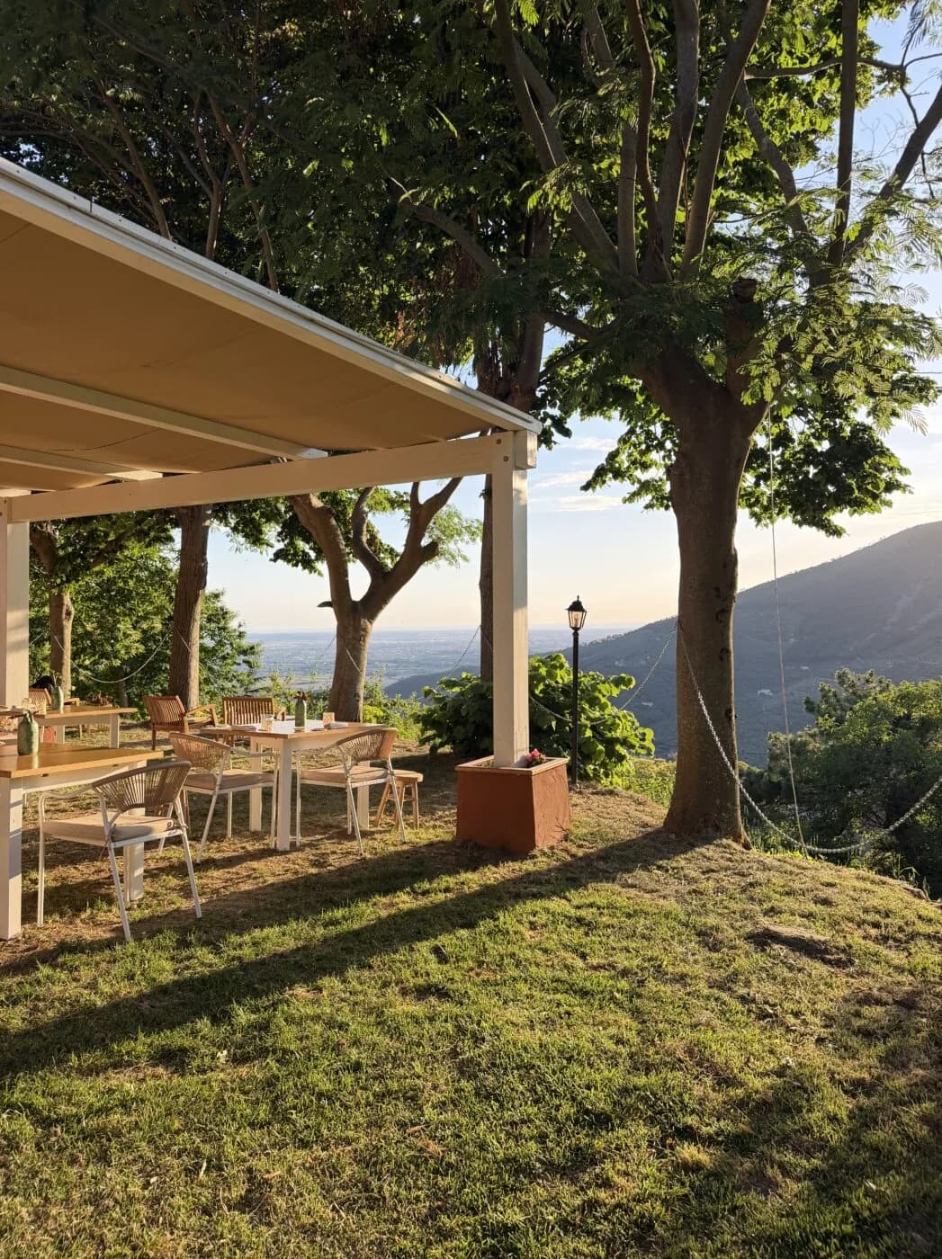 Il prato sotto la pergola, con i tavoli e la vista sulla piana di Pisa.