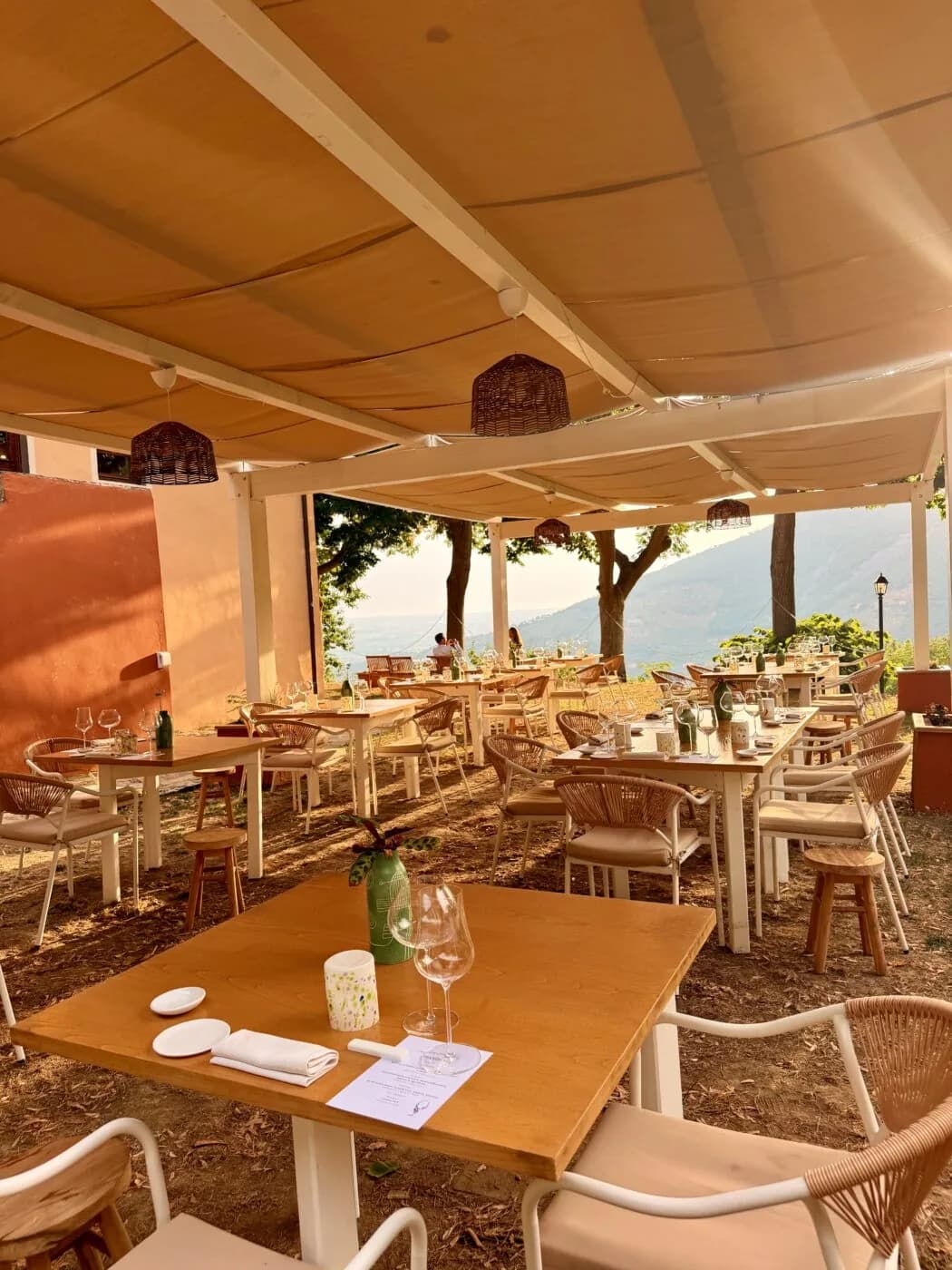 La terrazza del ristorante apparecchiata, tra gli alberi e la vista sulla valle.